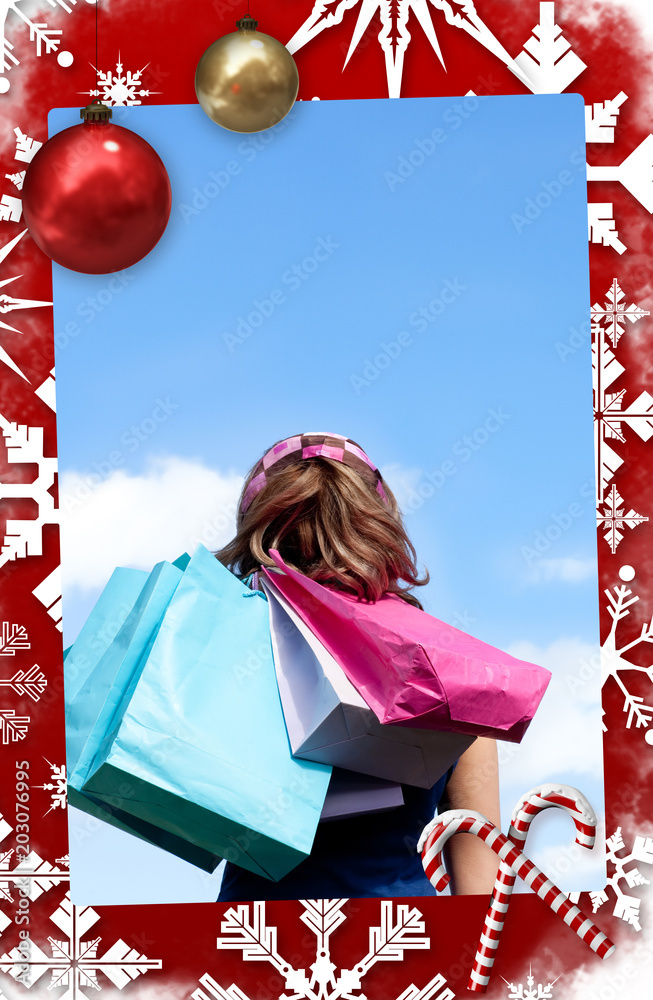 微笑的女人在户外拿着购物袋对着圣诞主题页面