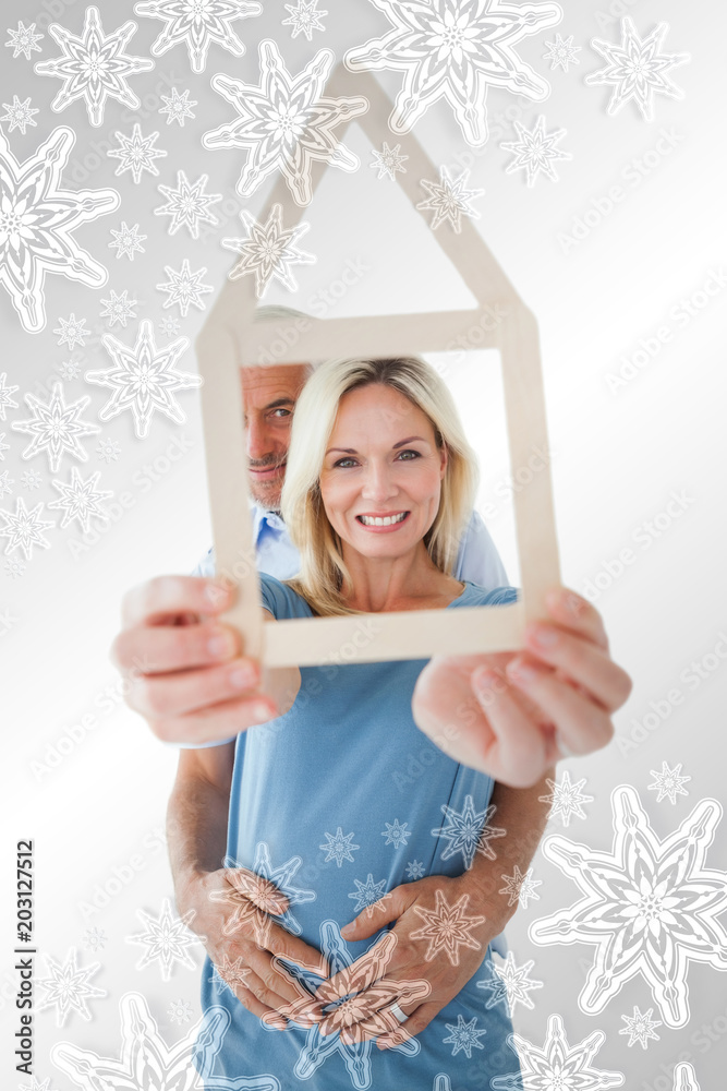 幸福的夫妇在银装素裹的雪花中展示房屋轮廓
