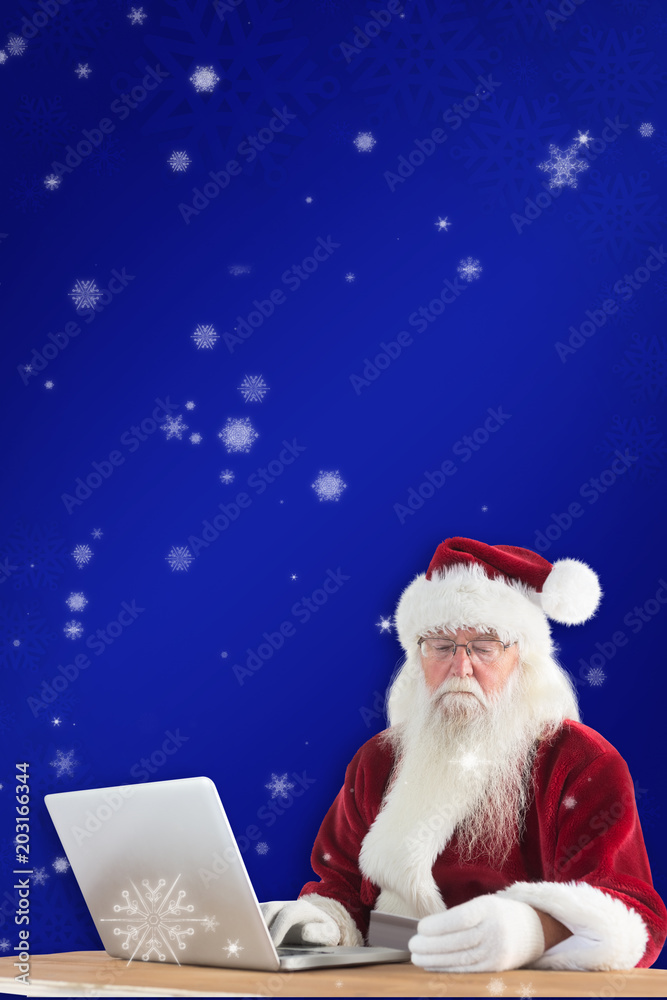圣诞老人在蓝色雪花背景下用笔记本电脑上的信用卡付款