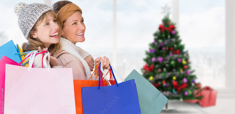 美丽的女人拿着购物袋，用圣诞树望着家