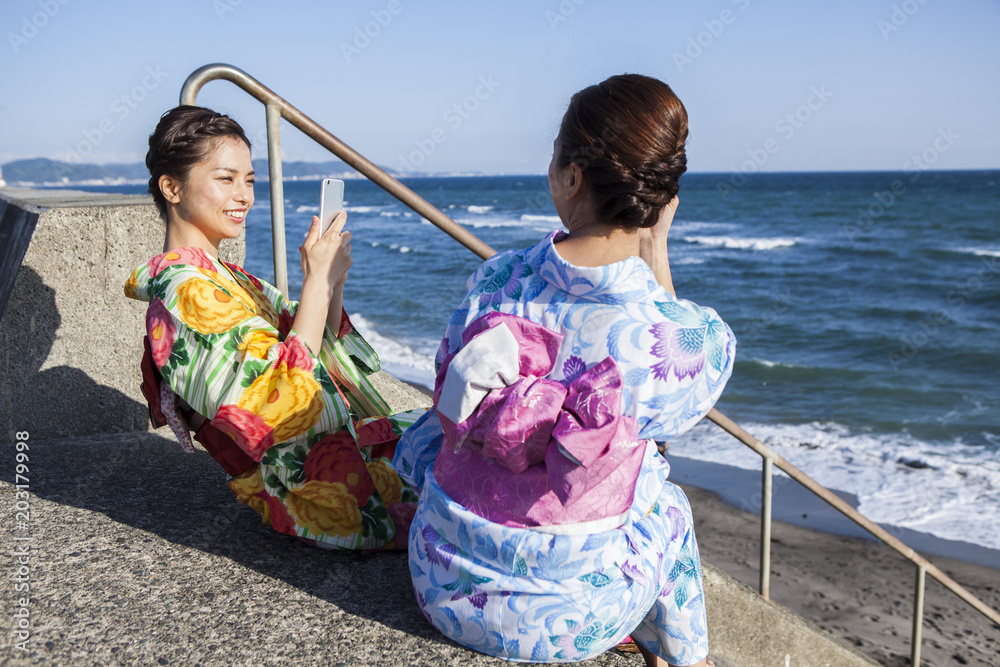 浴衣女性たちは海辺で写真を撮っている