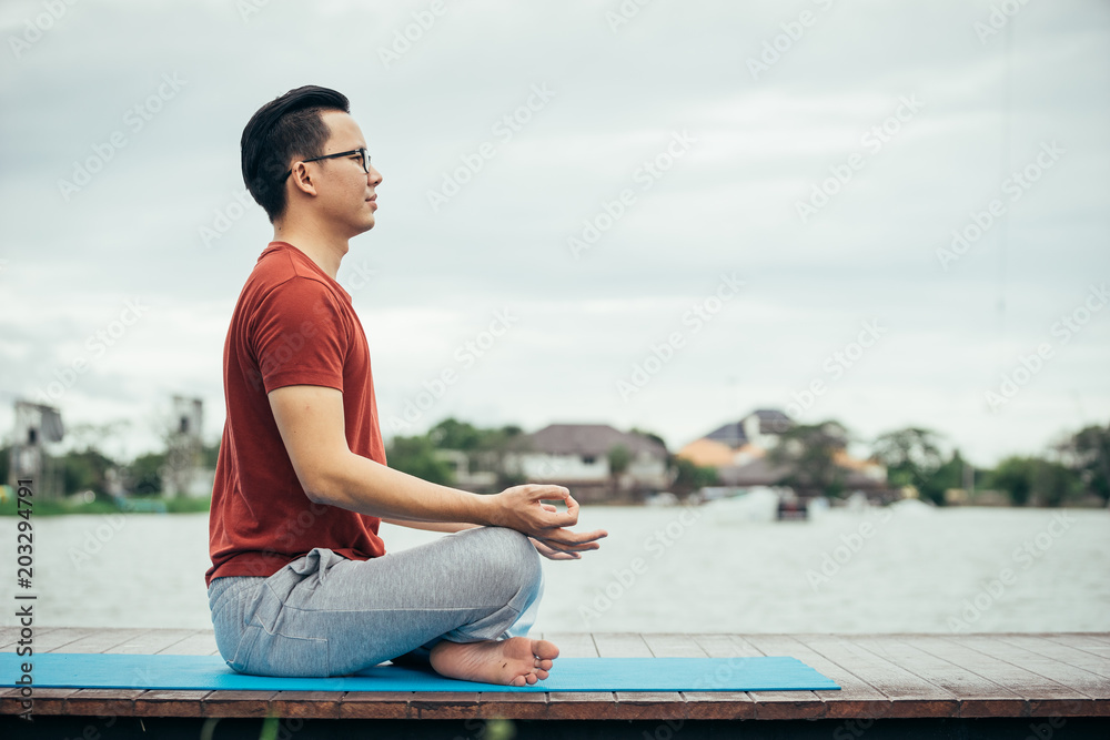 亚洲男子清晨在瑜伽课上与瑜伽学校玩耍。生活方式和健康概念。