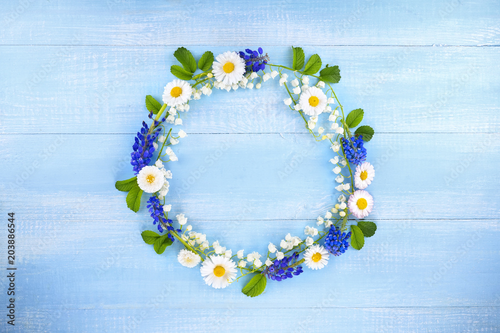 创意夏季春季花卉构图。白色雏菊、铃兰、五月制成的花环框架