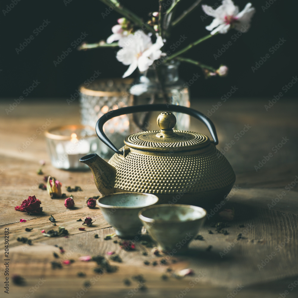 传统的亚洲茶道安排。金色的铁茶壶、杯子、蜡烛和杏仁花弗洛