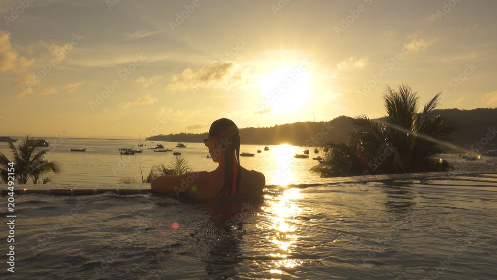 特写：美丽的女人在日落时看着令人惊叹的热带海边。