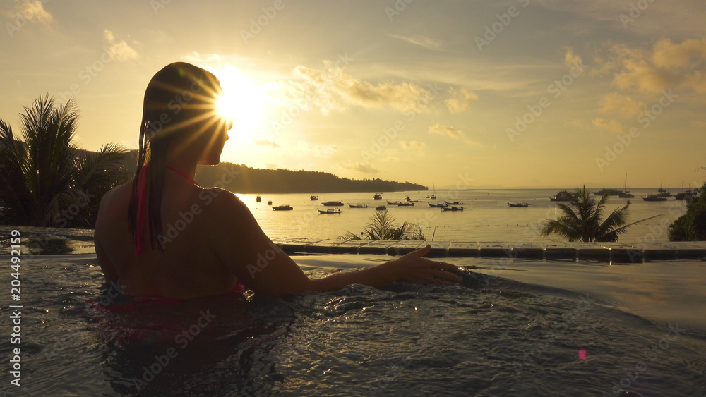特写：一位无忧无虑的年轻女子在日出时看着令人惊叹的异国海滩