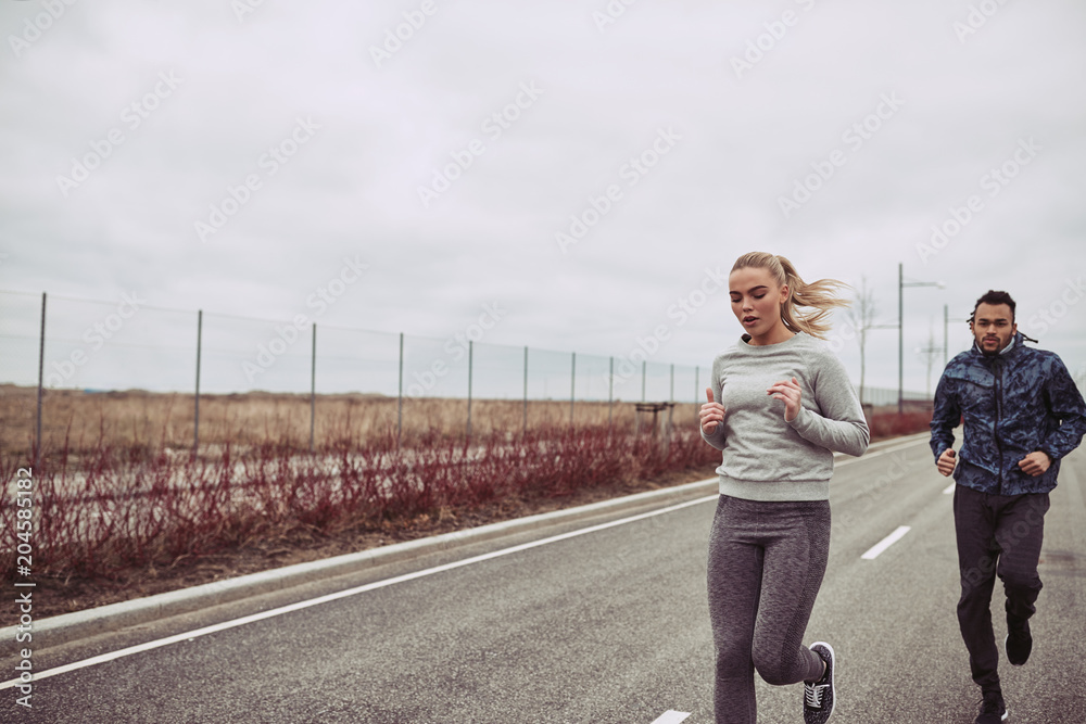 穿着运动服的多元化年轻情侣在乡间小路上慢跑