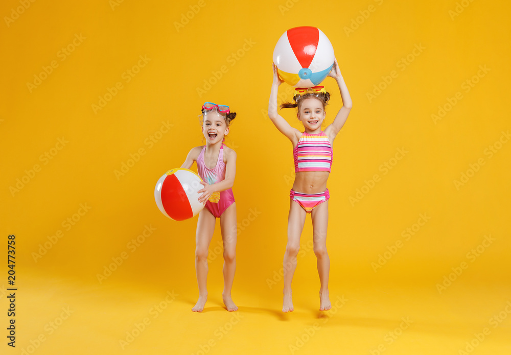 穿着泳衣的有趣快乐的孩子在彩色背景上跳跃