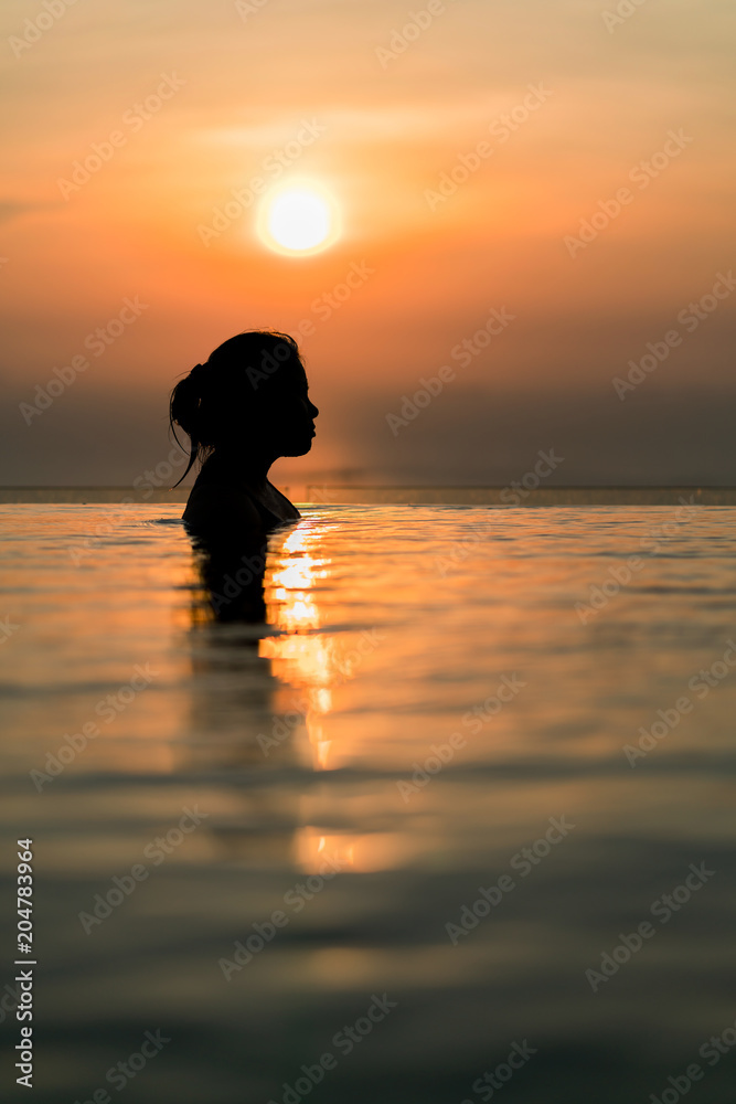 亚洲女性在暑假假期与b在无边泳池放松的黑色剪影