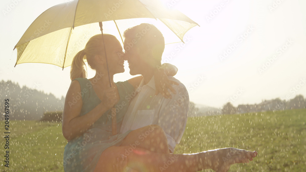 特写：这对被拥抱的年轻情侣在夏雨中跳舞时正要接吻。