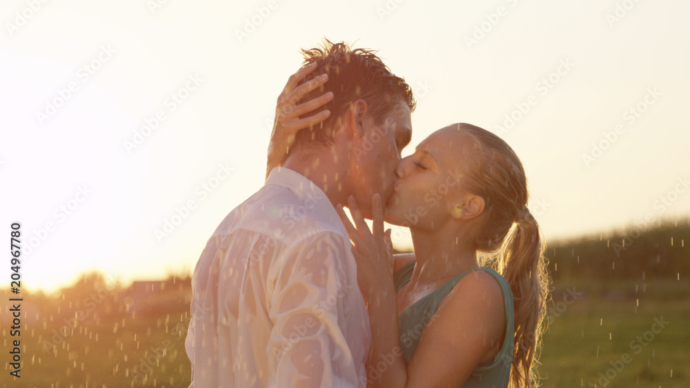 镜头闪光：金发女子抚摸男朋友在雨中接吻的脸。