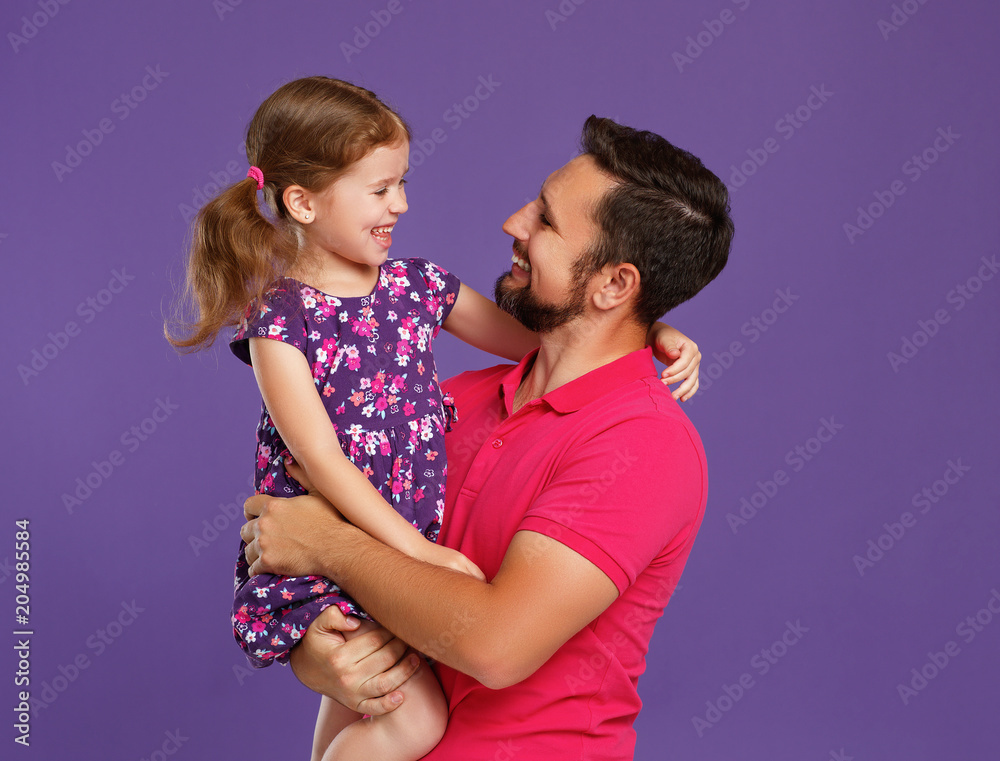 父亲节快乐！可爱的爸爸和女儿在紫色背景下拥抱。