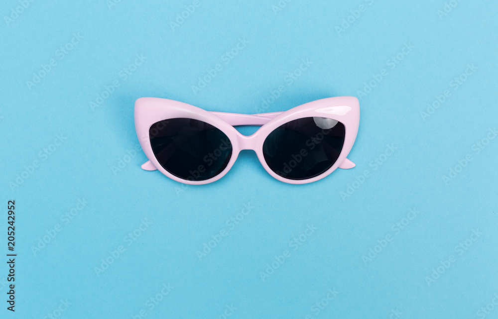 Cool sunglasses on a baby blue background, top view