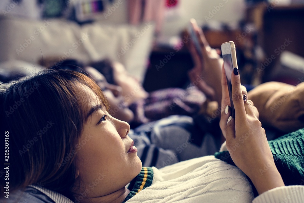 青少年女孩在床上使用智能手机参加睡眠派对