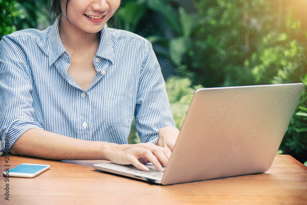 年轻的亚洲女商人坐在户外咖啡馆里用笔记本电脑。桌子上是笔记本电脑。businesswoma