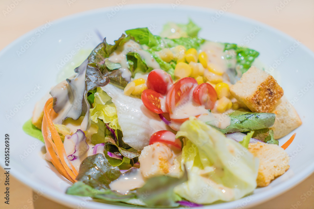 新鲜沙拉，配鸡肉、西红柿和混合绿色蔬菜（芝麻菜、梅斯克伦菜、马赫菜），装在木制的白碗里