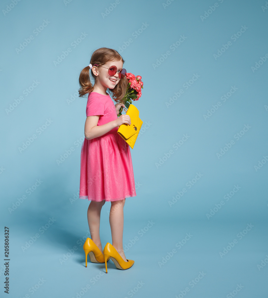 有趣的童女时尚达人，穿着彩色背景的大妈妈鞋。