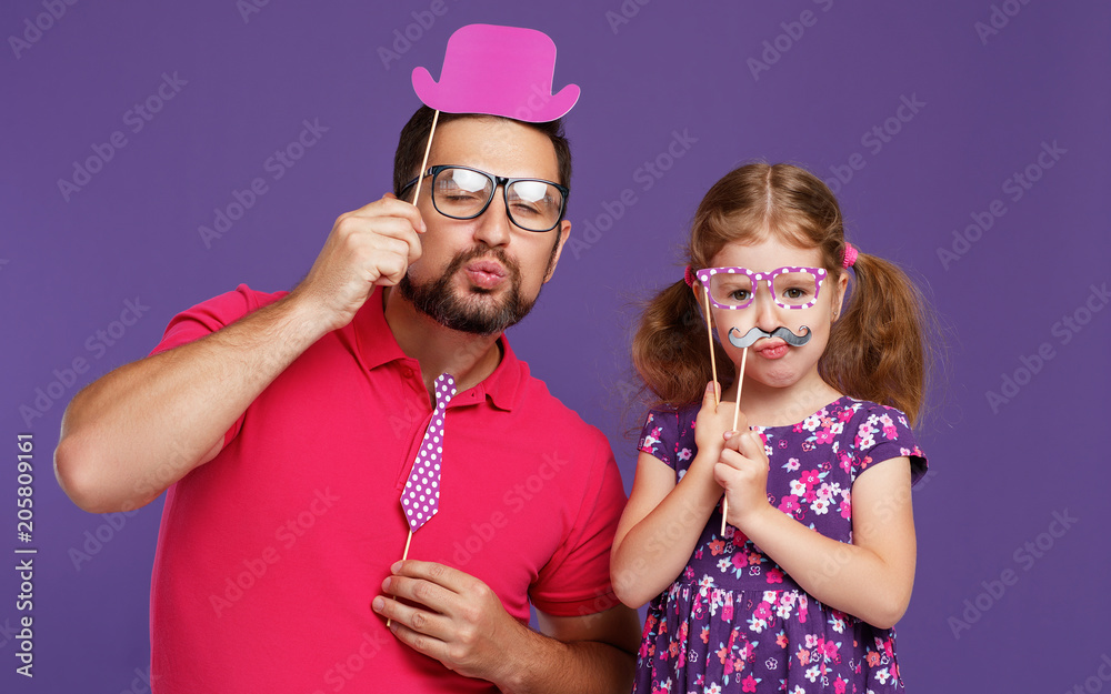 父亲节快乐！有胡子的爸爸和女儿在紫色背景下胡闹
