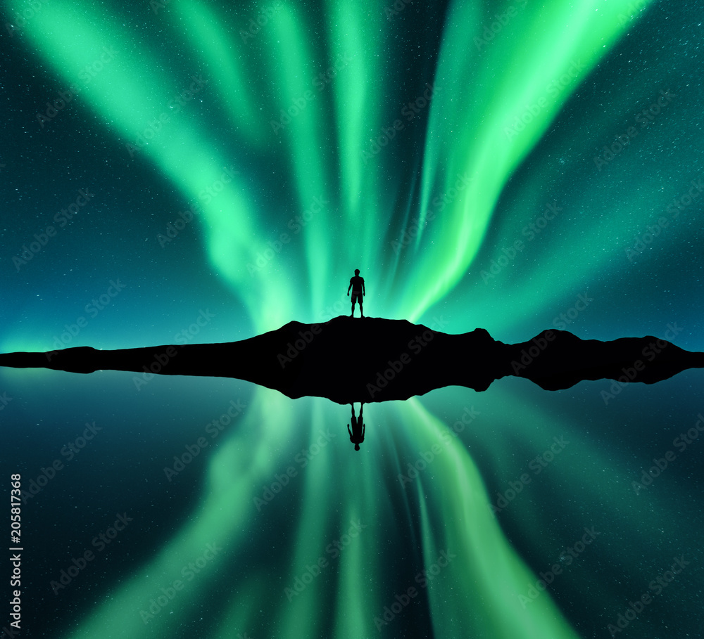 北极光和站着的人的剪影。挪威罗弗敦群岛。极光和快乐的人。星星