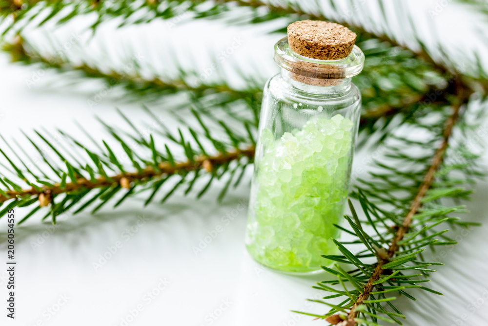 cosmetic spruce salt in bottles with fur branches on white table