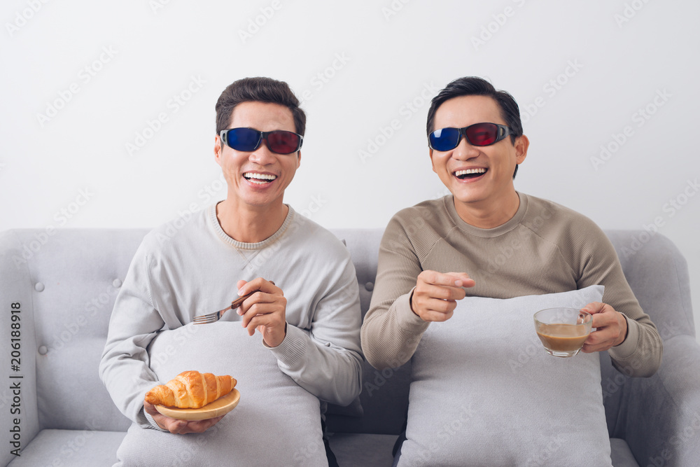 两个戴着3d眼镜的亚洲男人坐在沙发上看电影