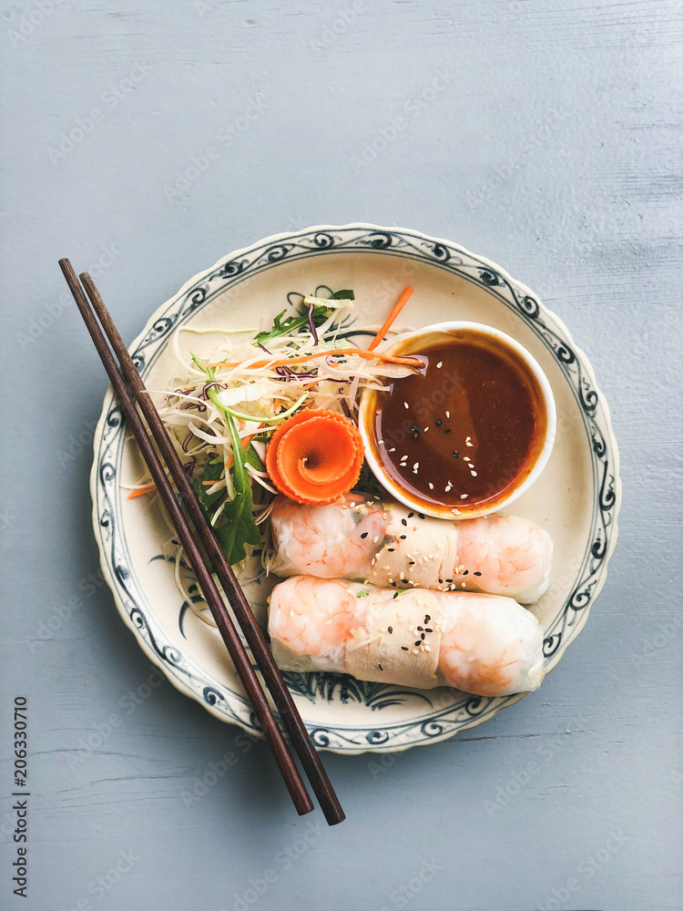 亚洲风格的晚餐。碗里放着虾和烧烤酱的扁平夏季宣纸卷