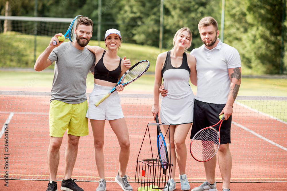 一群穿着运动服、拿着球拍站在户外网球场上的年轻朋友的肖像