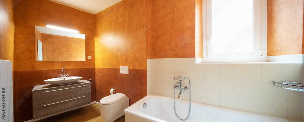 带有现代饰面和橙色墙壁的浴室