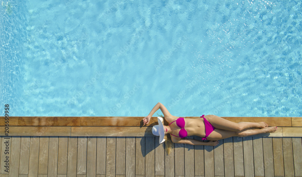 AERIAL华丽的年轻女子，身体迷人，在泳池边晒太阳