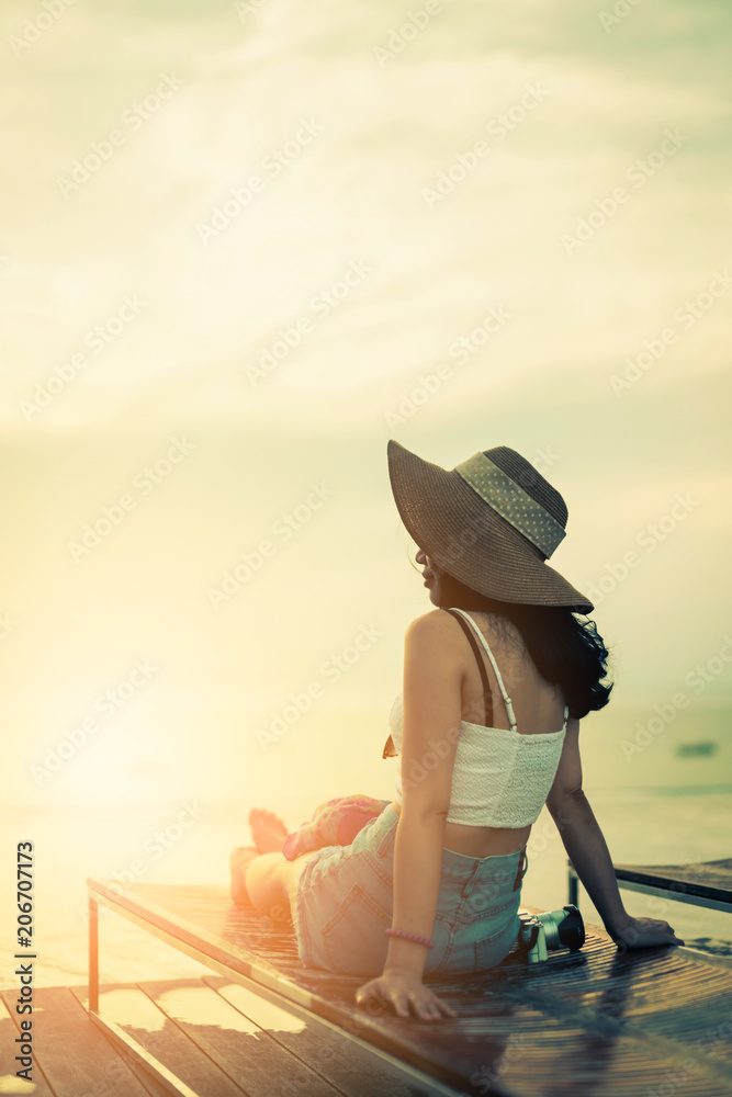 孤独的亚洲女人坐在木长椅上看着日落，情绪激动