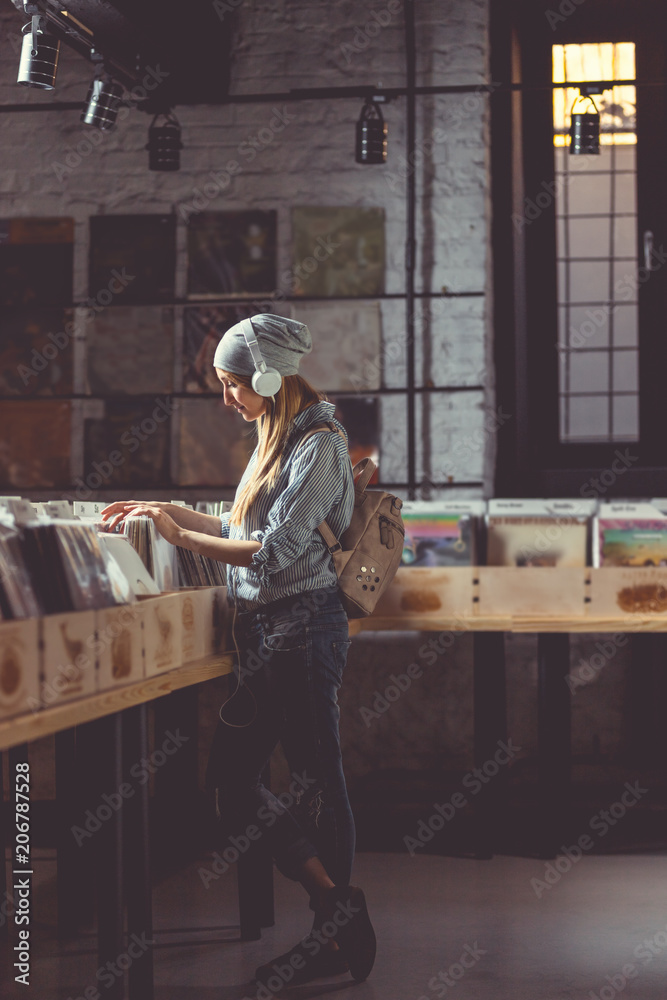 年轻女孩在黑胶唱片店里听音乐