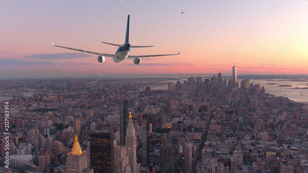 空中飞航：一架客机在美丽的日落时分飞越曼哈顿市中心。