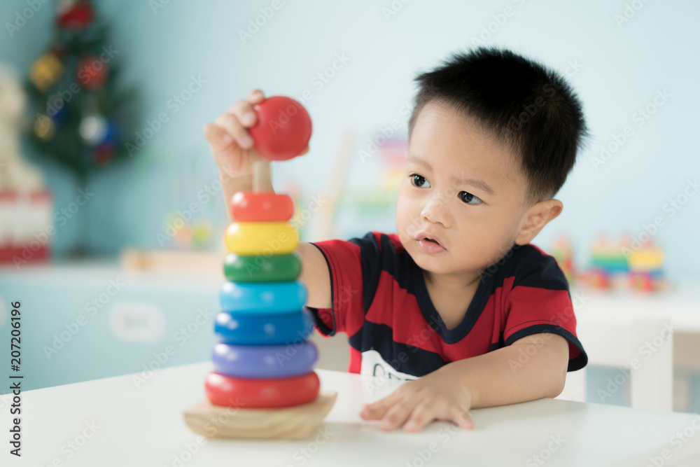 可爱的亚洲幼童坐在椅子上，在家里玩彩色发育玩具。
