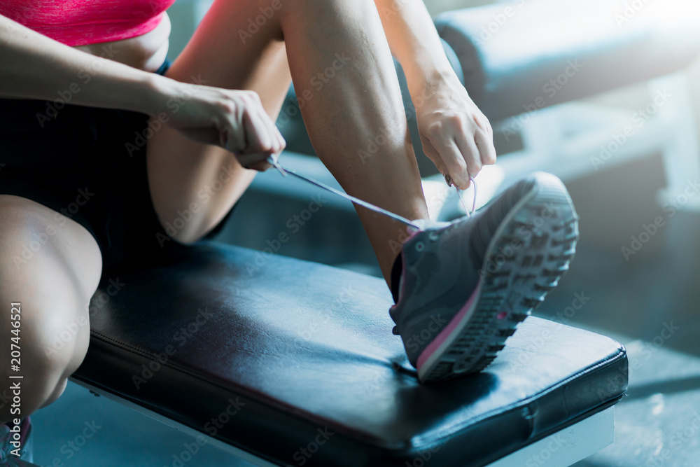 一名女子准备在健身房的长椅上穿着运动鞋锻炼