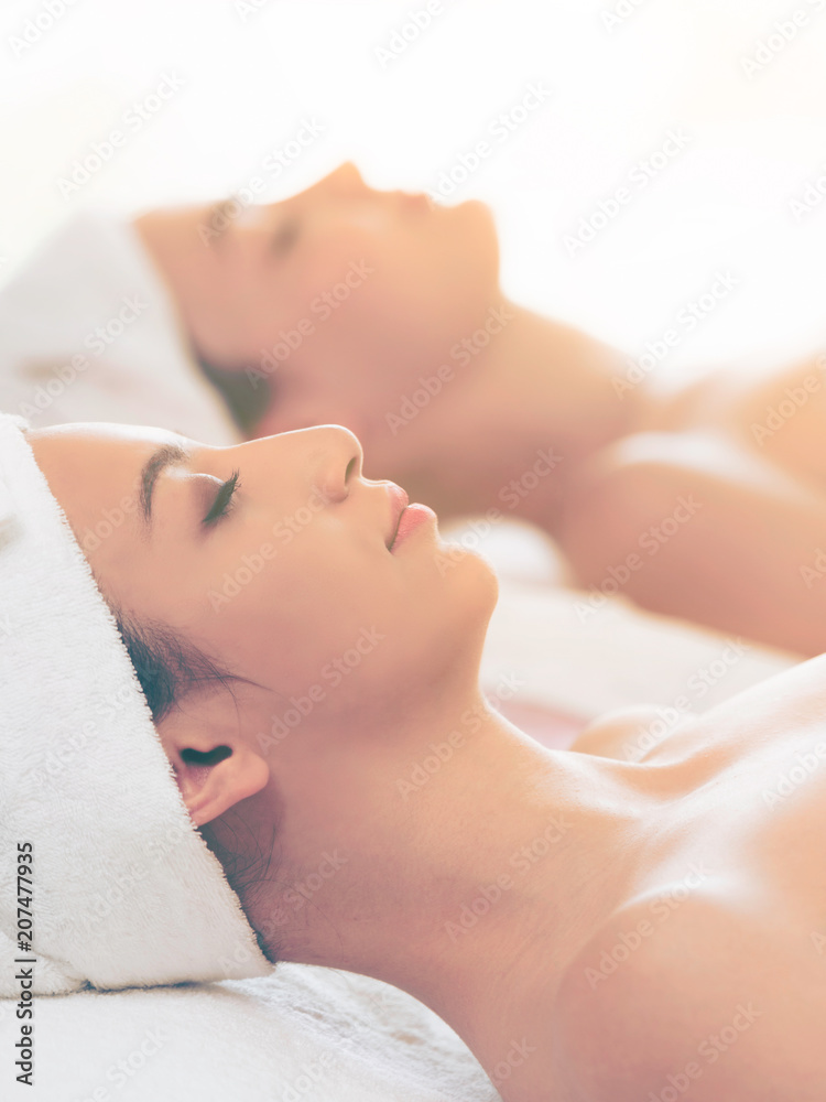 放松的年轻女子躺在水疗床上按摩。