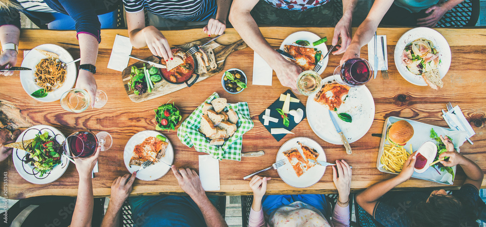 家人或朋友的夏季聚会或户外晚餐。一群人在咖啡馆的大桌子上平躺