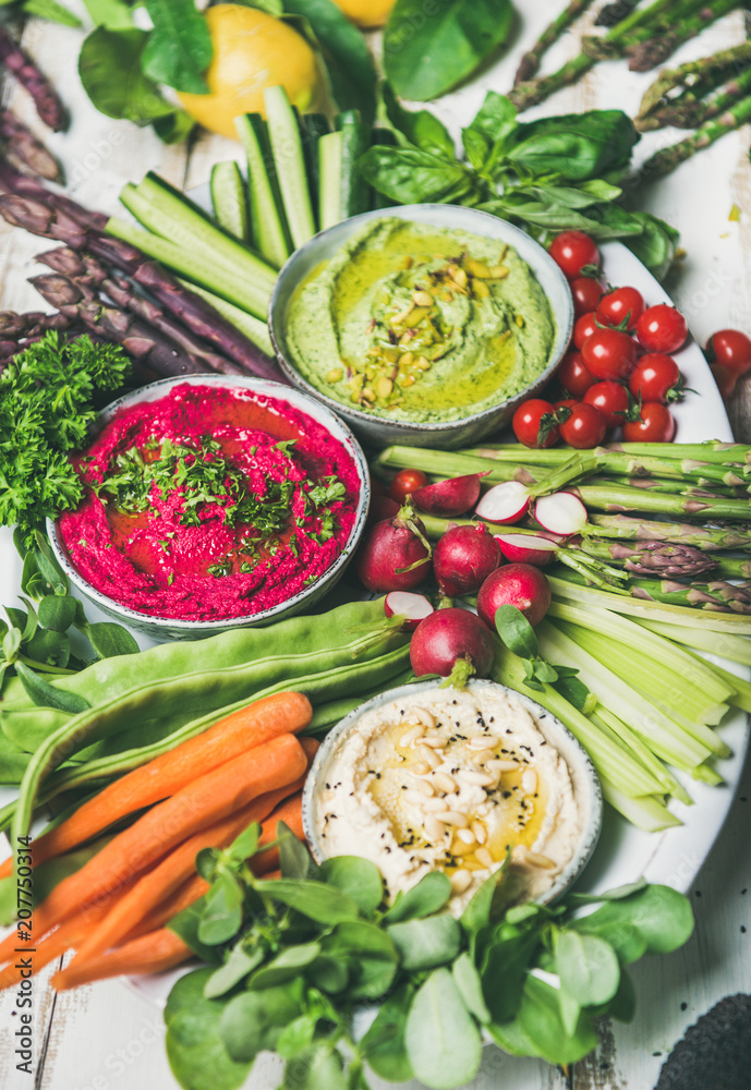 Healthy raw summer vegan snack plate. Chickpea, beetroot, spinach hummus dips with fresh vegetables 