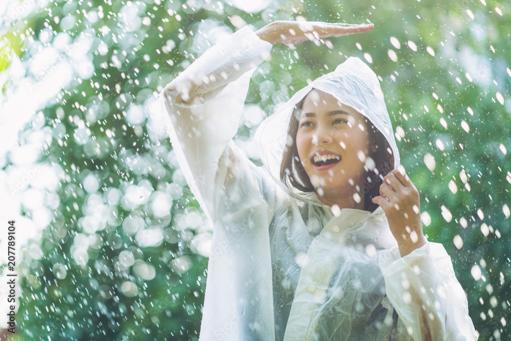 雨天，一个穿着雨衣的亚洲女人在户外。她很开心。