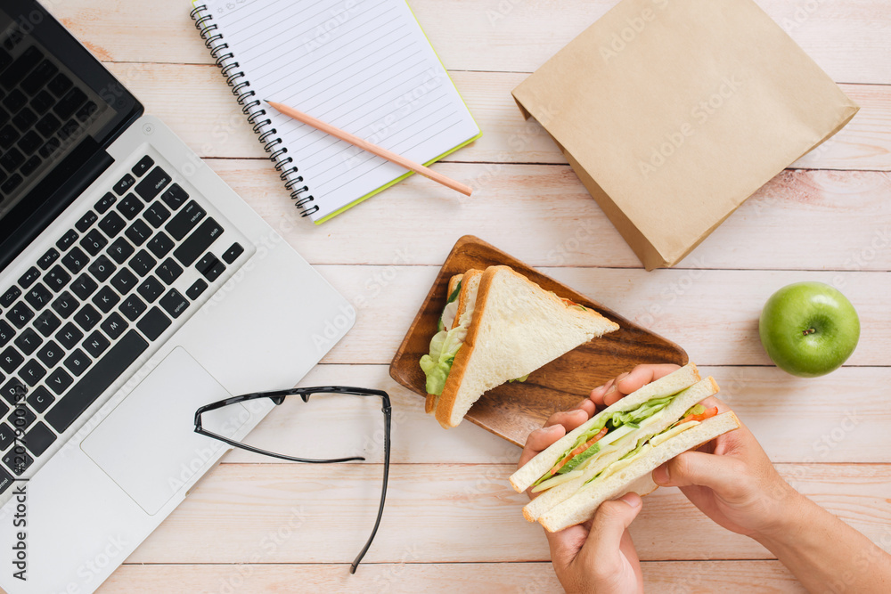 办公桌上有三明治和水果的午餐袋