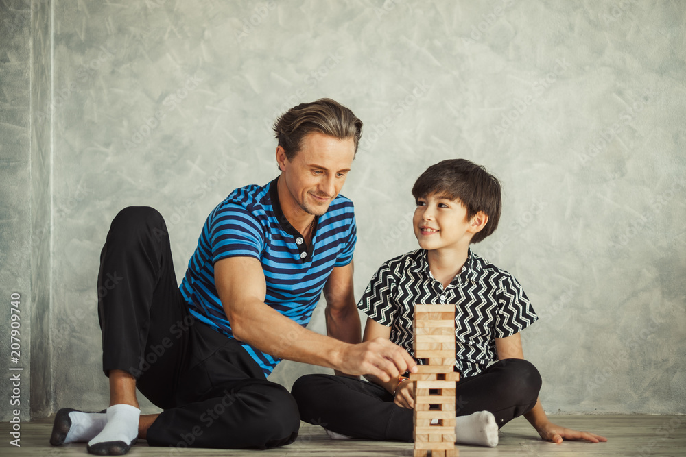 幸福的家庭，父亲和儿子玩积木，可爱的男孩坐在地上，快乐而微笑