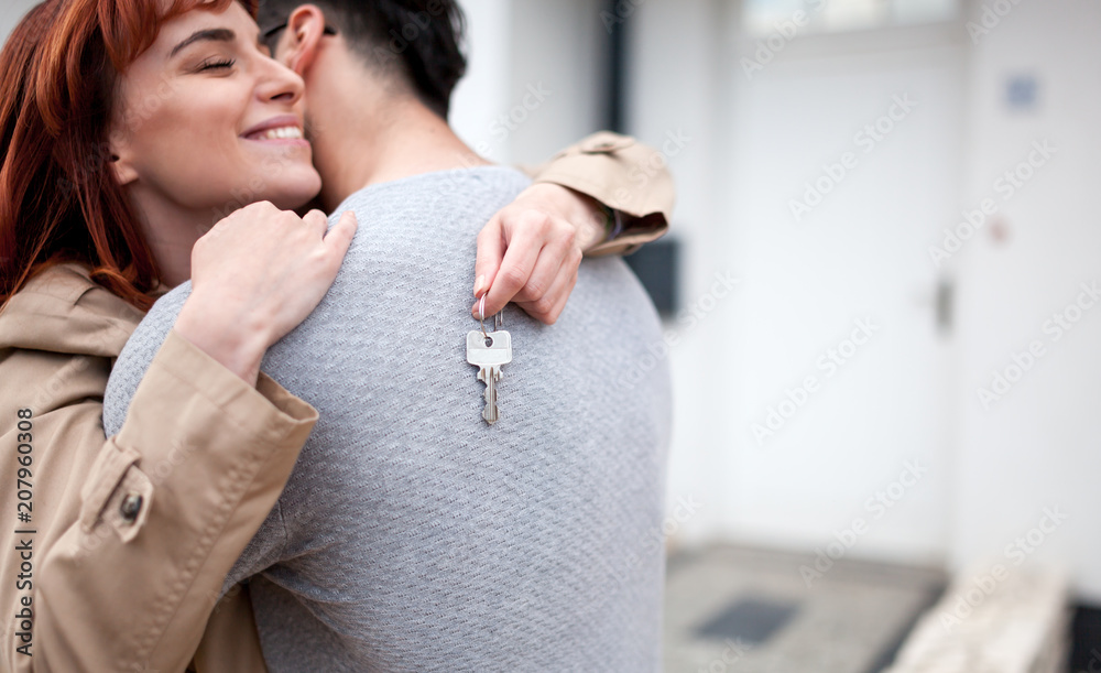 买了房地产，带钥匙的幸福夫妇在新房前拥抱