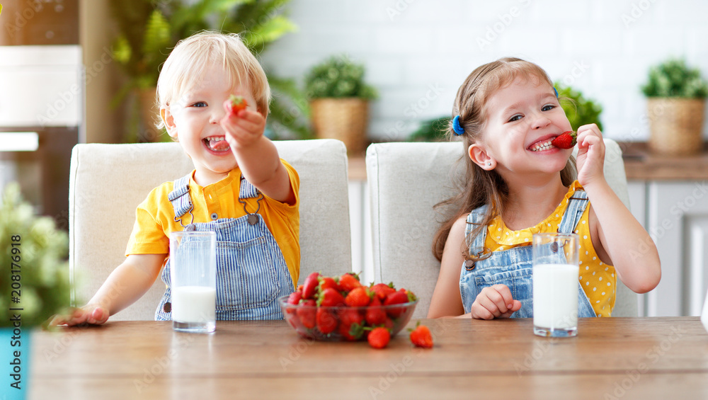 快乐的孩子兄弟姐妹一起吃草莓配牛奶