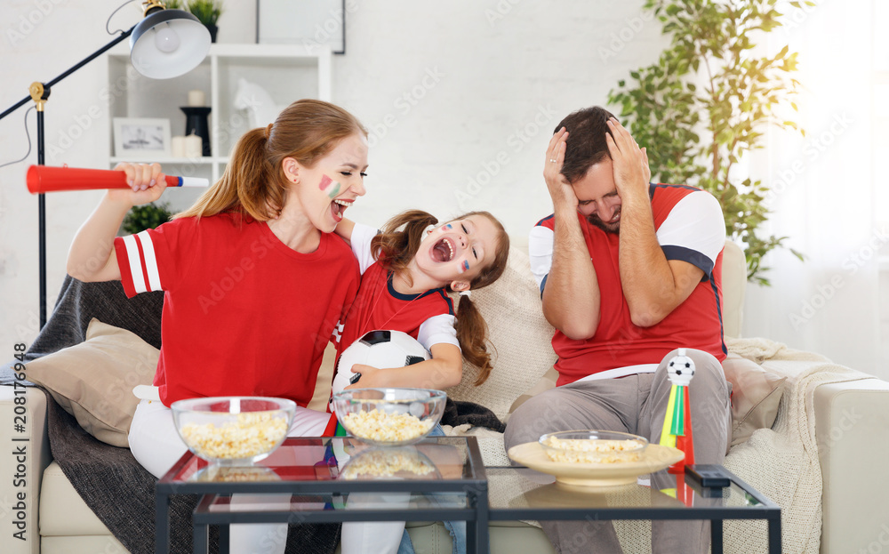 球迷的家人在家里看电视上的足球比赛。