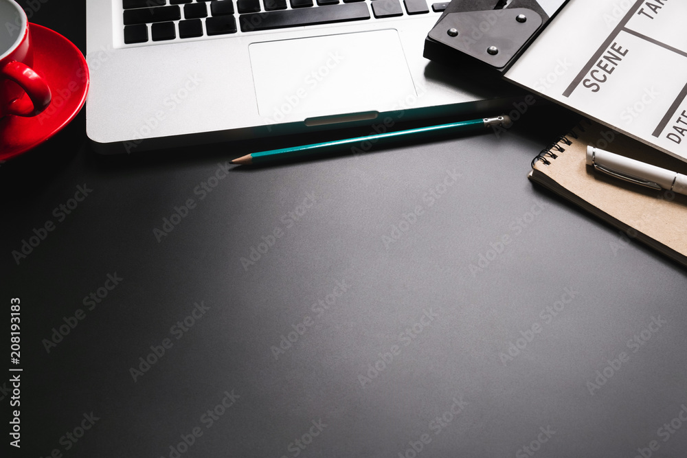 黑色桌面上有电影拍手笔记本电脑和咖啡杯笔记事本的办公室用品。