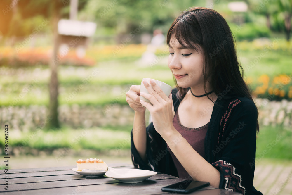 亚洲女性在家里的花园里喝杯咖啡放松身心，精神焕发。