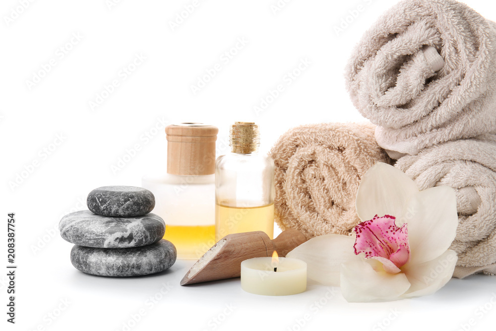Spa composition with rolled towels and stones on white background