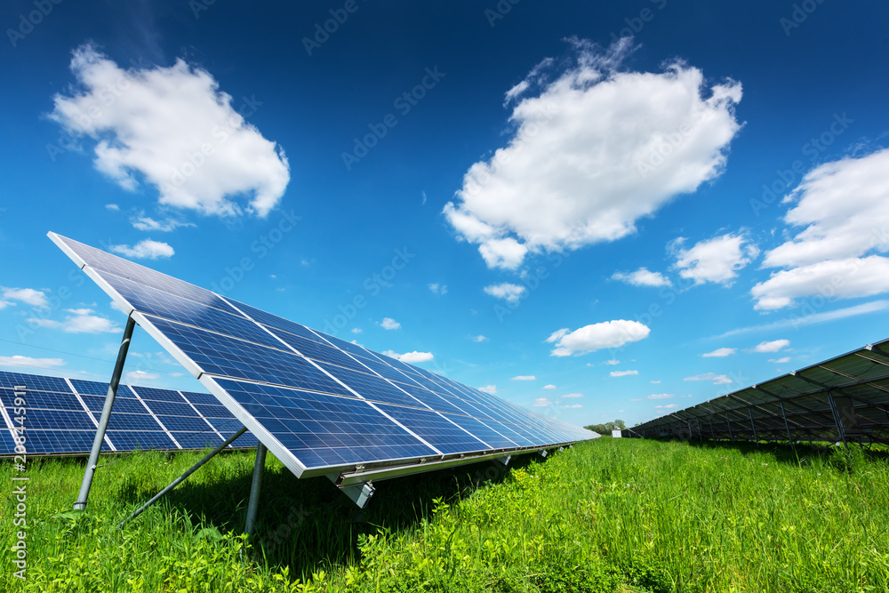 蓝天背景下的太阳能电池板。绿草和多云的天空。替代能源概念