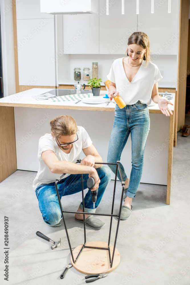 一对年轻可爱的夫妇在现代公寓的厨房里做家务，组装一把新椅子