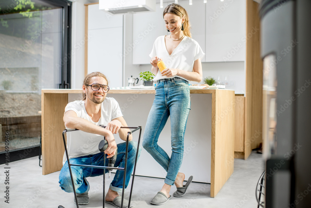年轻可爱的夫妇在现代公寓的厨房里做家务组装新椅子