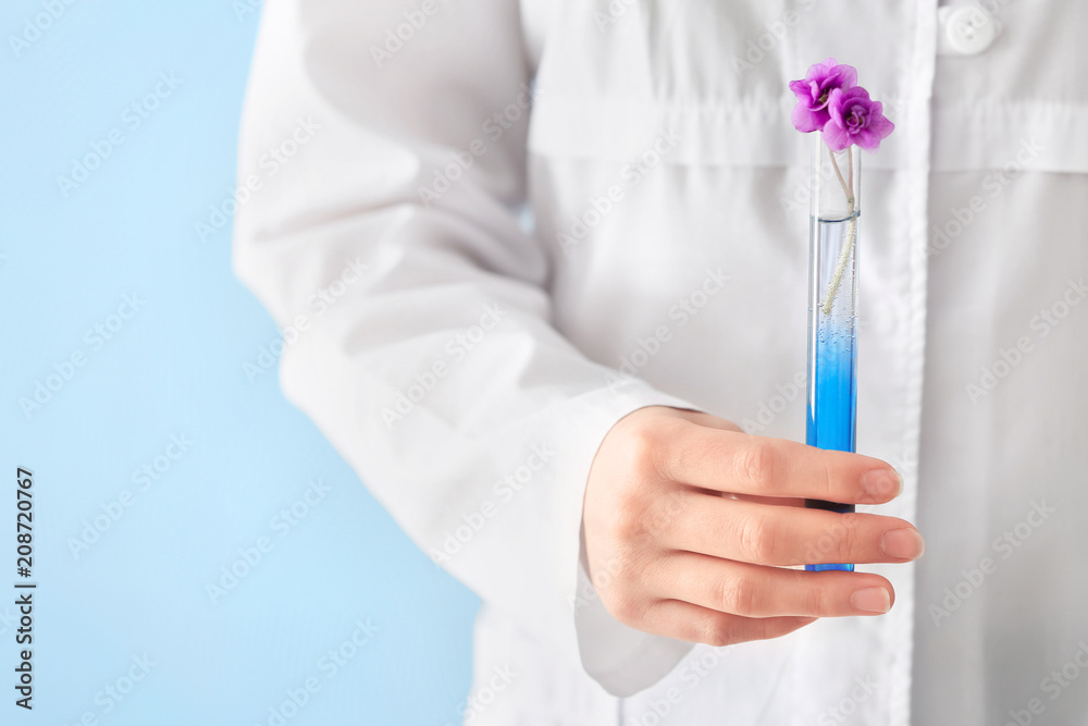 科学家拿着彩色背景上有花的试管